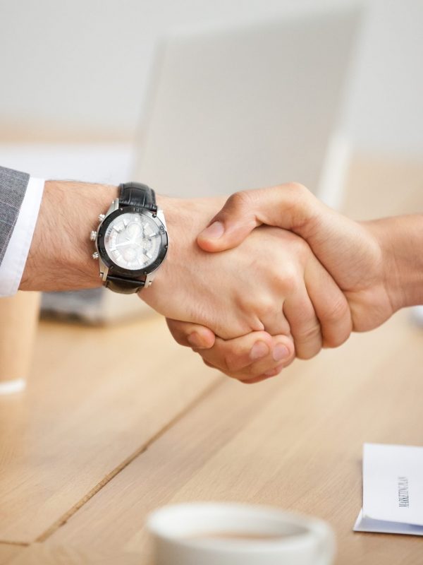 Close up view of handshake, two businessmen in suits shaking hands as concept of trust, good partnership deal, signing contract agreement at meeting, gratitude for help support in business